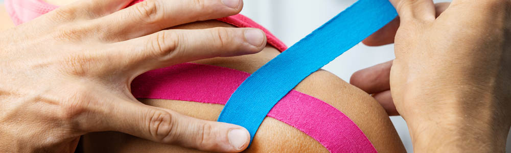 Kinesio taping being done on a young woman's shoulder Kinesio taping being done on a young woman's shoulder